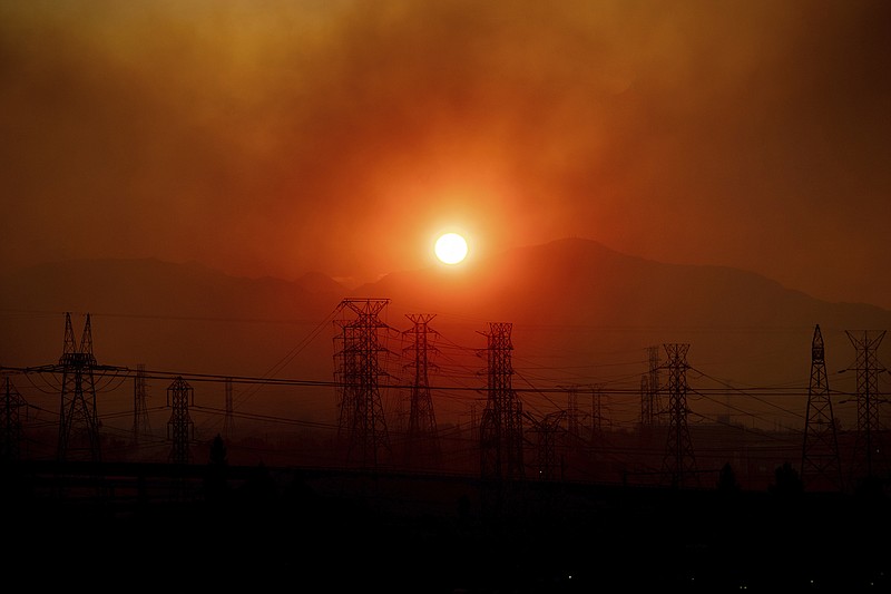 Smoke from the Saddleridge Fire hangs above power lines as the sun rises in Newhall, Calif., on Friday, Oct. 11, 2019. An aggressive wildfire in Southern California seared its way through dry vegetation Friday and spread quickly, destroying more than a dozen homes as tens of thousands of residents were ordered to get out of its way, authorities said. (AP Photo/Noah Berger)