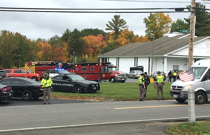 RETRANSMITTED WITH NEW SLUG AND BETTER QUALITY  - In this photo provided by WMUR-TV, police stand outside the New England Pentecostal Church after reports of a shooting on Saturday, Oct. 12, 2019, in Pelham, N.H. WMUR-TV reports that Hillsborough County Attorney Michael Conlon said a suspect is in custody. (Siobhan Lopez/WMUR-TV via AP)