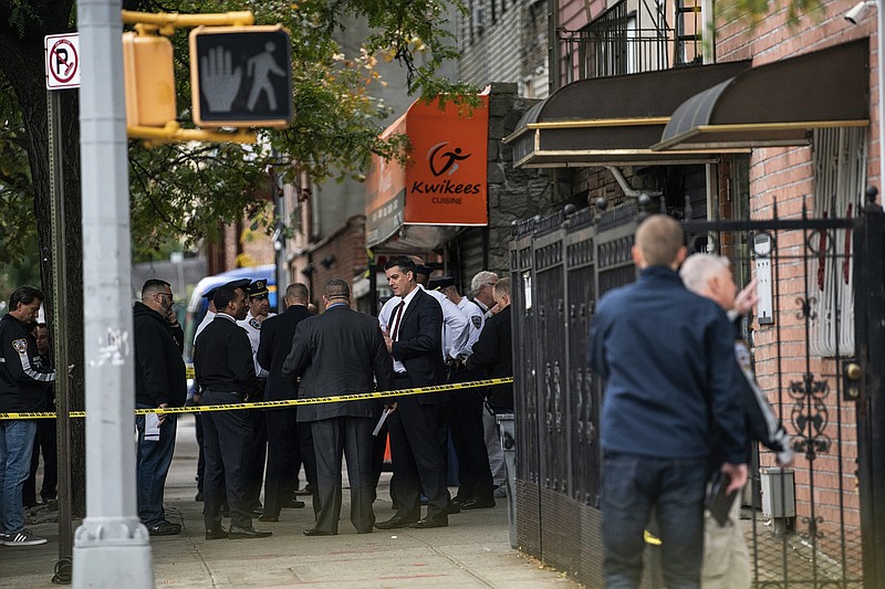 NYPD investigates the scene of a shooting in the Brooklyn borough of New York on Saturday, Oct. 12, 2019.  Authorities responded to a call about shots fired just before 7 a.m. and found four men dead in the Crown Heights neighborhood of Brooklyn at an address that corresponds to a private social club according to an online map of the street.  A woman and two men suffered non-life-threatening injuries.  (AP Photo/Jeenah Moon)