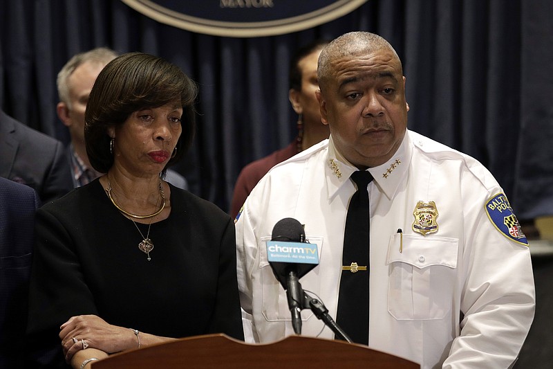 IN this Feb. 11, 2019 photo, Baltimore Mayor Catherine Pugh, left, and Michael Harrison, center, acting commissioner of the Baltimore Police Department, listen to a reporter's question at an introductory news conference for Harrison in Baltimore. Police say a 2-year-old boy was wounded by gunfire when someone shot into a vehicle in an act of road rage, Saturday, Oct. 12.  Harrison says the boy is in "somewhat stable condition" and is expected to survive. (AP Photo/Patrick Semansky, File)