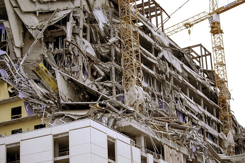 Debris hangs on the side of the building after a large portion of a hotel under construction suddenly collapsed in New Orleans on Saturday, Oct. 12, 2019. Several construction workers had to run to safety as the Hard Rock Hotel, which has been under construction for the last several months, came crashing down. It was not immediately clear what caused the collapse or if anyone was injured.  (Scott Threlkeld/The Advocate via AP)