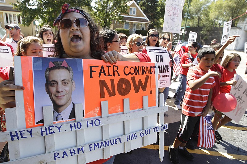 FILE - This Sept. 10, 2012 file photo shows Striking Chicago Public School teachers picketing as Mayor Rahm Emanuel visits with students taking part at the Safe Haven program during a teachers strike in Chicago. A threatened strike in 2019 by Chicago teachers would carry on the city's historically significant role in education labor disputes, including the 2012 strike cited by teachers around the country as inspiration for walkouts and other protests in recent years. That seven-day strike was a dramatic test of the Chicago Teachers Union's effort to force expanded negotiations into social issues beyond the typical give-and-take over pay and benefits. (AP Photo/M. Spencer Green, File)