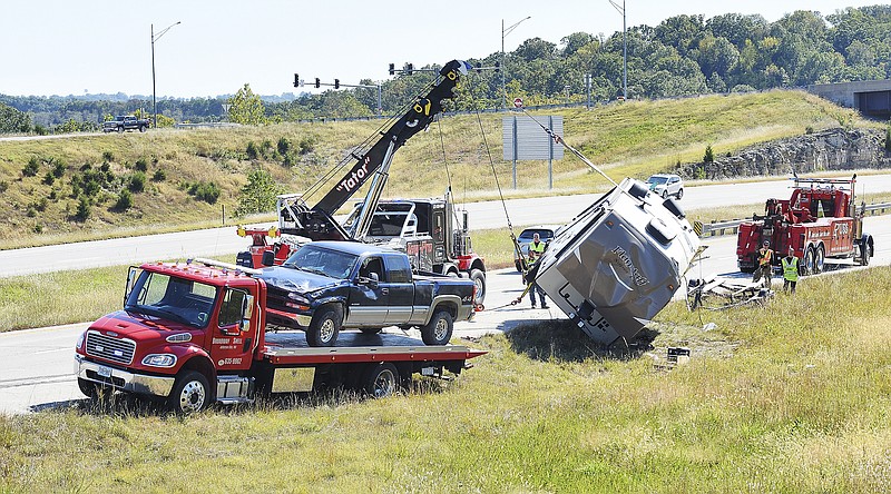 Julie Smith/News Tribune
Tow Pro Wrecker operators work to upright a fifth-wheel camper Monday afternoon. The camper was the middle vehicle of three damaged in the traffic crash that occurred shortly after noon. The driver and passenger were reportedly uninjured after the boat trailer being towed behind a fifth-wheel camper sustained a blown tire causing the trailer to fishtail behind the camper. Eventually the momentum caught up with the camper and truck causing all three to run off the right side of westbound U.S. 54, just north of the Rt. 179 overpass, where they came to rest on their sides. According to the Jefferson City Police Department, the accident occurred about 12:19 p.m., causing westbound traffic to be slowed to one lane during the cleanup. 