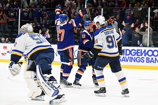 Blues goaltender Jordan Binnington and teammate Vladimir Tarasenko skate away as the Islanders celebrate after scoring a goal in overtime Monday in Uniondale, N.Y.