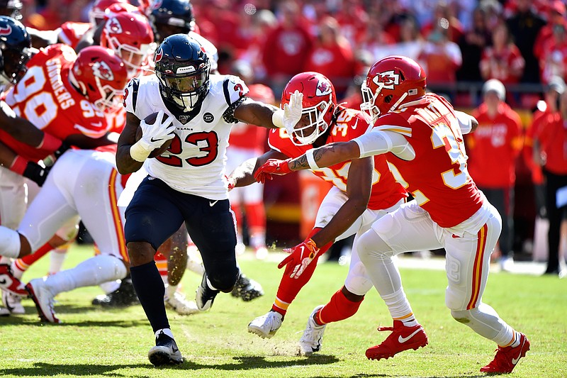 Houston Texans running back Carlos Hyde (23) carries the ball against Kansas City Chiefs safety Tyrann Mathieu (32) and cornerback Charvarius Ward (35) during the second half of an NFL football game in Kansas City, Mo., Sunday, Oct. 13, 2019. (AP Photo/Ed Zurga)