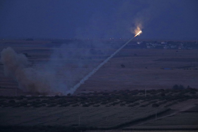 In this photo taken from the Turkish side of the border between Turkey and Syria, in Ceylanpinar, Sanliurfa province, southeastern Turkey, Turkish forces fire rockets towards targets in Ras al-Ayn, Syria, Tuesday, Oct. 15, 2019. (AP Photo/Lefteris Pitarakis)