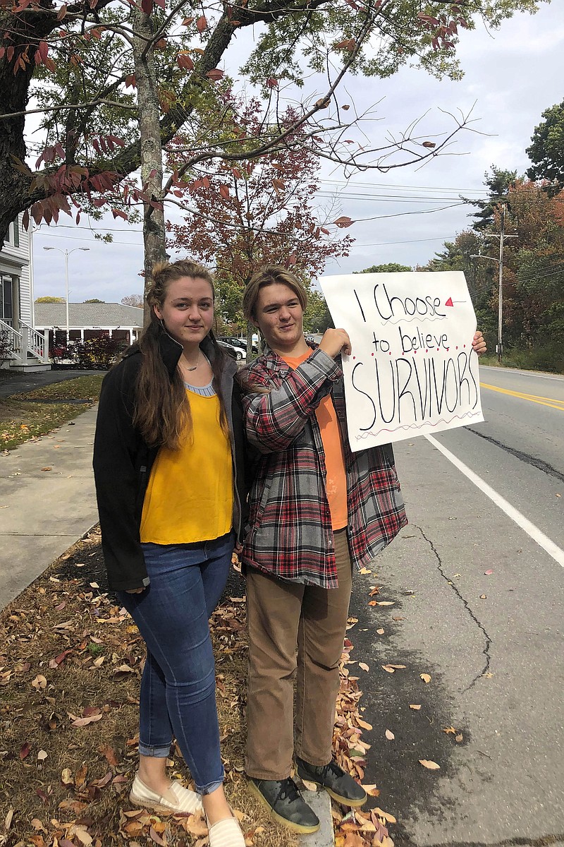 In this Monday, Oct. 7, 2019 photo provided by Shael Norris, high school sophomore Aela Mansmann, 15, of Cape Elizabeth, Maine, left, stands with her brother Aidan, 13, as he displays a placard during a school walkout, in Cape Elizabeth. The American Civil Liberties Union of Maine is calling on a federal court to stop the suspension of Aela Mansmann who accused an unnamed person of sexual assault. Aela and Aidan participated in the school walkout meant to protest the suspension of Aela and two other students. (Shael Norris via AP)