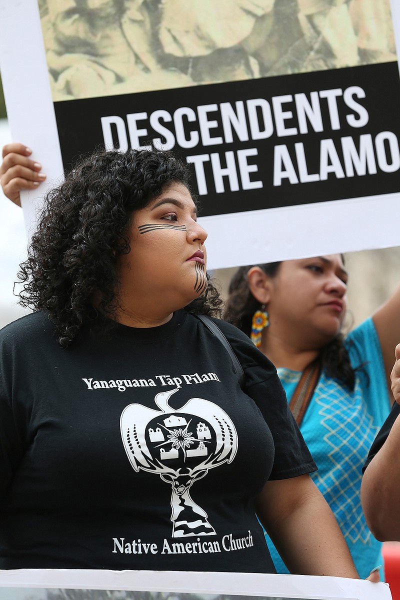 Alexis Reyes joins other members of the Native American community during a news conference by the U.S. Postal Service building across the Alamo, Monday, Oct. 14, 2019 in San Antonio. A Native American group is calling on officials to slow down the renovation of the Alamo church in San Antonio, after archaeological reports showed human remains were found at the property. (Jerry Lara/The San Antonio Express-News via AP)