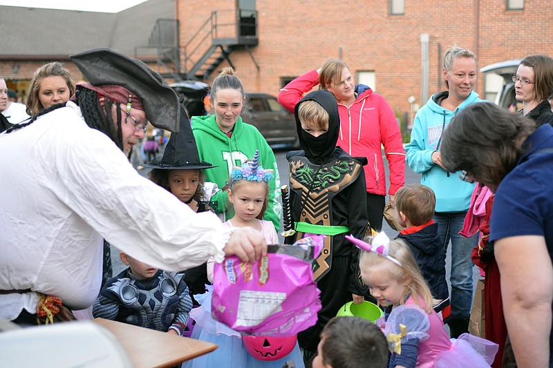 <p>News Tribune file photo</p><p>Tim Gilzow, left, hands out candy during the 2018 Trunk or Treat at Cornerstone Baptist Church.</p>