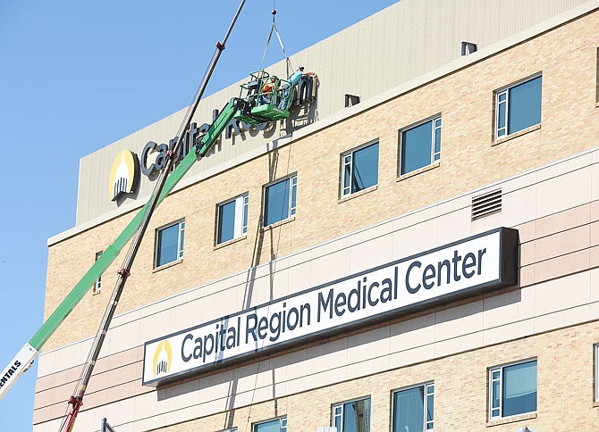 FILE PHOTO: Workers steady the new piece as a crane operator Caleb Prenger lifts the "Region" part of the new sign into place at Capital Region Medical Center on October 16, 2019. The workers are part of Bee Seen Signs in Apache Flats and will take down the older box-type sign currently mounted on the same side of the building.