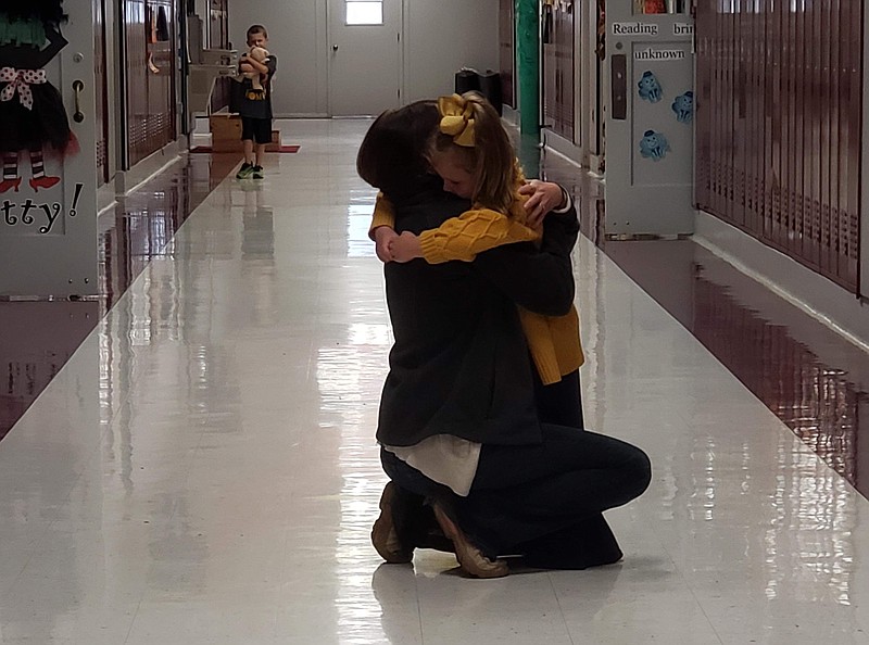 McLeod Elementary first-grader Ava Murdock receives a hug from teacher Jessica Downs on Monday in the school hallway. Ava's teacher, Jessica Baig, was killed in a car wreck Sunday, along with her husband and daughter. The school has been flooded with support from the community, churches and area school districts as they work to find peace through the tragedy of losing a teacher and student. (Submitted photo)

