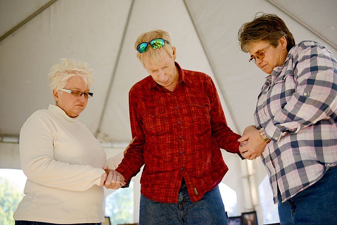 From left, Sharon Williams, Alan Jean Varrin and Tammy Smith pray together Thursday during a tent revival on the Capitol lawn. This was Varrin's first time attending a tent revival. The tent is one of three locations in the state for a 50-hour nationwide prayer and worship service.