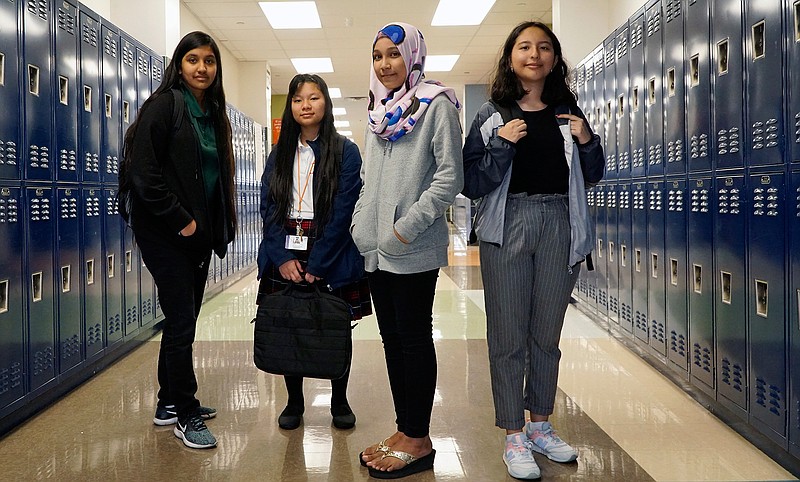 In this Thursday, Oct. 3, 2019 photo, from left, Liliana Chavez, 13, Hser Eh Doh, 13, Syahira Noor Bashar, 13, and Briana Barron, 15, pose at Tasby Middle School in Dallas, Texas. The girls helped create a guide for immigrant students new to the United States. (Lawrence Jenkins/The Dallas Morning News via AP)