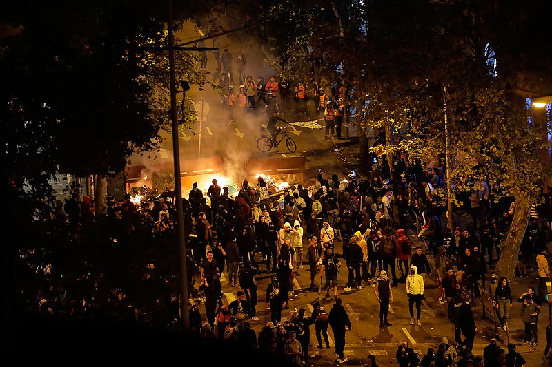 Demonstrators stand by a burning barricade in Barcelona, Spain, Saturday, Oct. 19, 2019. Barcelona and the rest of the restive Spanish region of Catalonia are reeling from five straight days of violent protests for the sentencing of 12 separatist leaders to lengthy prison sentences.The riots have broken out at nightfall following huge peaceful protests each day since Monday's Supreme Court verdict. (AP Photo/Manu Fernandez)