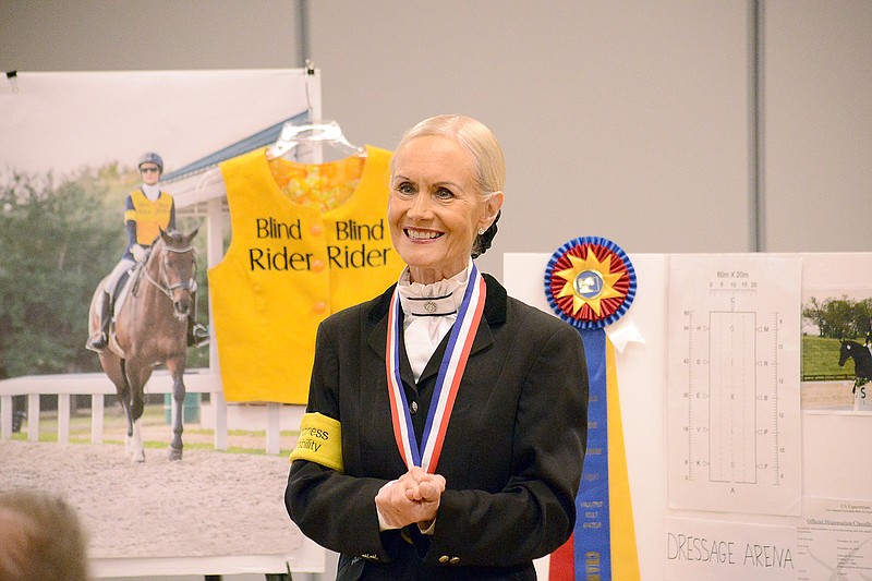 Deborah McAlexander stands in front of a picture of her riding her horse, Cornet Noir, as she speaks Tuesday during a "Stronger Through Diversity" series at The Linc. McAlexander is legally blind and hopes to compete in the 2020 Paralympic Games and 2022 World Equestrian Games.