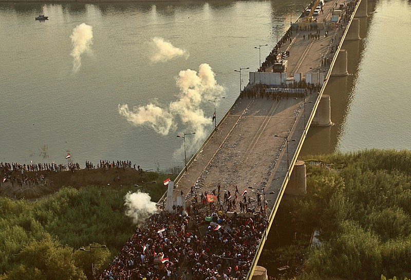 Security forces fire tear gas and close the bridge leading to the Green Zone during a demonstration in Baghdad, Iraq, Saturday, Oct. 26, 2019. Iraqi protesters converged on a central square in the capital Baghdad on Saturday as security forces erected blast walls to prevent them from reaching a heavily fortified government area after a day of violence that killed scores. (AP Photo/Hadi Mizban)