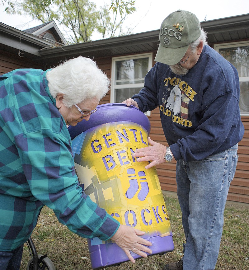 Janet and Ed Miller apply a stencil to a purple barrel. The couple used the barrel to collect socks for the needy in memory of their son, Ben.