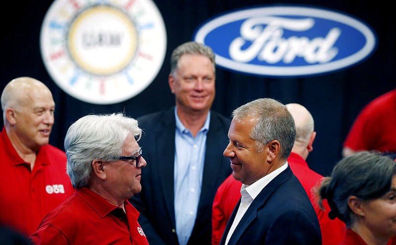 In this Monday, July 15, 2019, file photo, United Auto Workers Local 600 President Bernie Ricke, left, talks with Ford Motor Co., President Automotive Joseph R. Hinrichs after opening contract talks in Dearborn, Mich. The United Auto Workers union said late Wednesday, Oct. 30 that it has reached a tentative contract agreement with Ford after three days of intense bargaining. (AP Photo/Carlos Osorio, File)