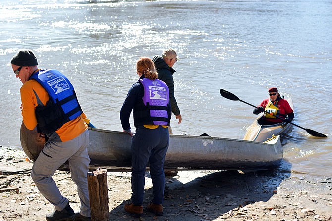 Boaters carry their canoe and kayak in from the river Saturday as they reach the finish line at the Wilson's Serenity Point at Noren Access during 10th annual Race to the Dome event. 