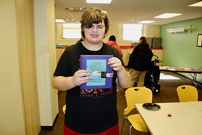 Fulton High School senior Marshall Gibson shows off his "smash book" Friday afternoon at the Callaway County Public Library. Gibson designed the cover to emphasize his upcoming May graduation date and fashioned a strap to keep the book closed.