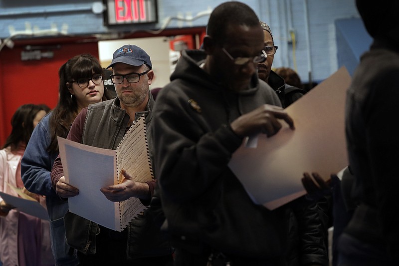 In this Nov. 6, 2018 file photo, voters read their ballot papers as they wait in line to cast their vote at P.S. 161 in Brooklyn borough of New York. A ballot measure will give New York City residents a chance to institute ranked choice voting in primaries and special elections. Under the system now in effect in cities such as San Francisco and Cambridge, Massachusetts as well as the entire state of Maine, voters can rank candidates in order of preference instead of choosing just one.(AP Photo/Wong Maye-E, File)