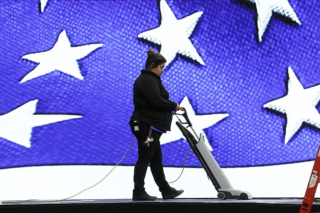 A worker vacuums the stage Friday before the Iowa Democratic Party's Liberty and Justice Celebration begins in Des Moines, Iowa. 