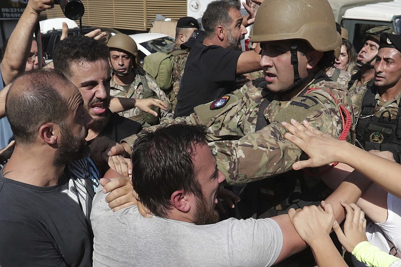 Anti-government protesters scuffle with Lebanese army soldiers in the town of Zouk Mosbeh, north of Beirut, Lebanon, Tuesday, Nov. 5, 2019. Lebanese troops deployed in different parts of the country Tuesday reopening roads and main thoroughfares closed by anti-government protesters facing resistance in some areas that led to scuffles. (AP Photo/Hassan Ammar)