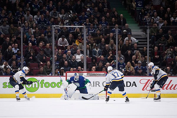 Jaden Schwartz (17) of the Blues scores against Canucks goalie Jacob Markstrom (25) as the Blues' Brayden Schenn (10) and Alex Pietrangelo (27) watch during overtime in Tuesday night's game in Vancouver, British Columbia.