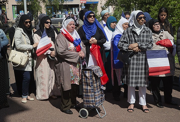 In this May 16, 2014 file photo, women wear muslim scarf and hold French flags gather outside the town hall of Mantes la Ville, northwest of Paris. The French Senate approved a bill Tuesday proposed by the mainstream right that would oblige women wearing headscarves to remove them when accompanying school outings. The bill has almost no chance of becoming law since the lower chamber, controlled by President Emmanuel Macron's centrist party, will almost certainly axe it. (AP Photo/Michel Euler, File)