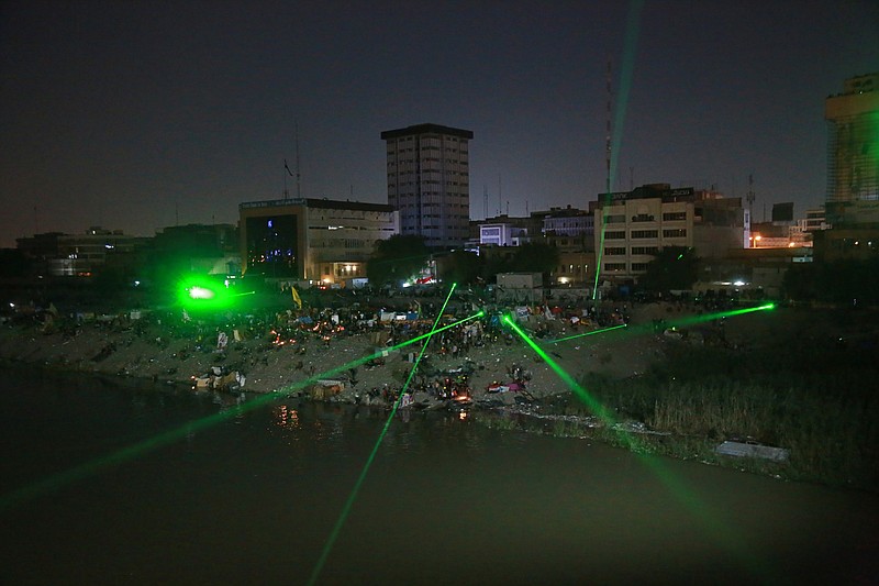 Anti-government protesters shoot laser lights at security forces during clashes on a bridge leading to the Green Zone government areas during ongoing protests in Baghdad, Iraq, Wednesday, Nov. 6, 2019. Tens of thousands of people have taken to the streets in recent weeks in the capital, Baghdad, and across the Shiite south, demanding sweeping political change. (AP Photo/Khalid Mohammed)