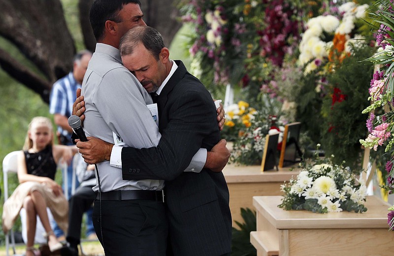 Men embrace next to the coffins of Dawna Ray Langford, 43, and her sons Trevor, 11, and Rogan, 2, who were killed by drug cartel gunmen, during the funeral at a family cemetery in La Mora, Sonora state, Mexico, Thursday, Nov. 7, 2019. Three women and six of their children, all members of the extended LeBaron family, died when they were gunned down in an attack while traveling along Mexico's Chihuahua and Sonora state border on Monday. (AP Photo/Marco Ugarte)