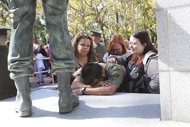 In this Oct. 23, 2019 photo, James Hernandez is comforted by Stacey Pollard, Terri Hernandez and Taylor Hernandez as hundreds turned out for the Beirut Memorial Observance at Lejeune Memorial Gardens in Jacksonville, N.C. . Pollard lost her father William Pollard and Hernandez lost his father Matilde Hernandez in the 1983 bombing attack. (John Althouse/The Jacksonville Daily News via AP)