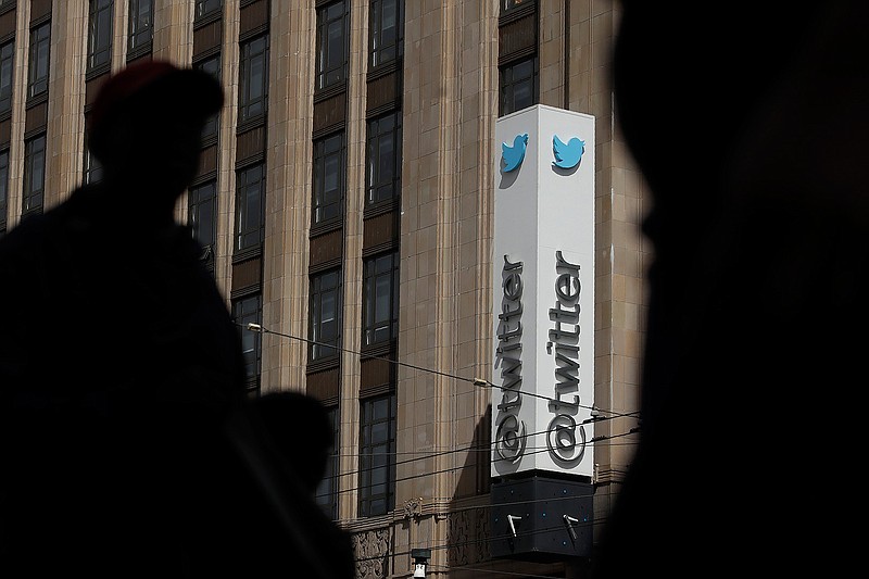 This July 9, 2019, file photo shows pedestrians walking across the street from the Twitter office building in San Francisco. The Saudi government recruited two Twitter employees to get personal account information of their critics, prosecutors said Wednesday, Nov. 6, 2019. (AP Photo/Jeff Chiu, File)