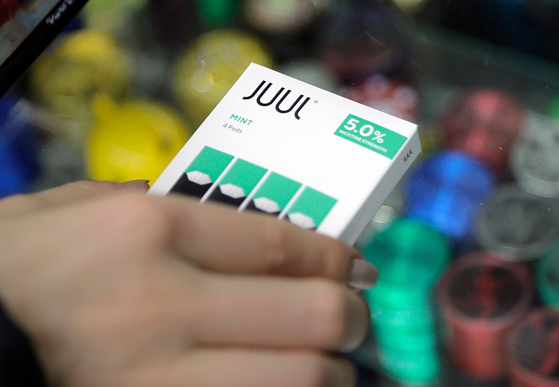 In this Dec. 20, 2018, file photo a woman buys refills for her Juul at a smoke shop in New York. The e-cigarette maker Juul Labs said Thursday, Nov. 7, 2019, that it will halt sales of its best-selling mint-flavored vaping pods. (AP Photo/Seth Wenig, File)