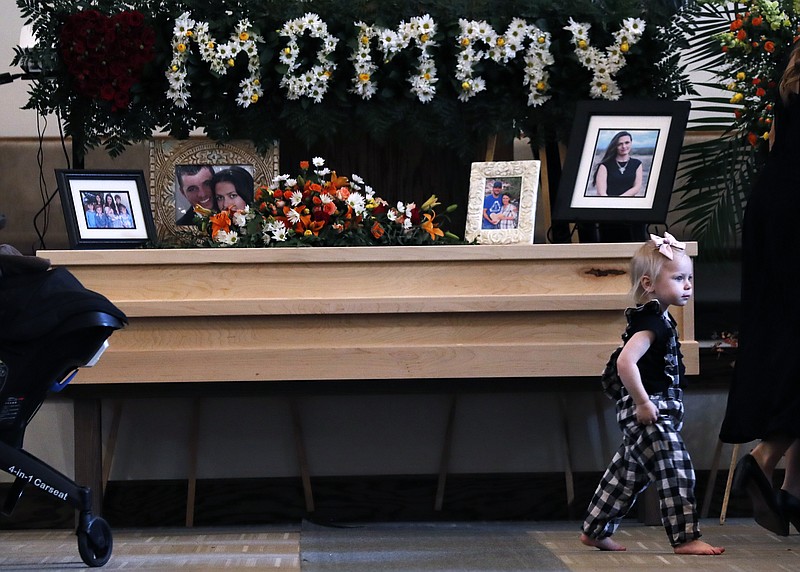 A child walks past a coffin that contain the remains of Christina Langford Johnson the last victim of a cartel ambush that killed nine American women and children earlier this week, in Colonia Le Baron, Mexico, Saturday, Nov. 9, 2019. In the attack Monday, Langford Johnson jumped out of her vehicle and waved her hands to show she was no threat to the attackers and was shot twice in the heart, community members say. Her daughter Faith Marie Johnson, 7 months old, was found unharmed in her car seat.  (AP Photo/Marco Ugarte)