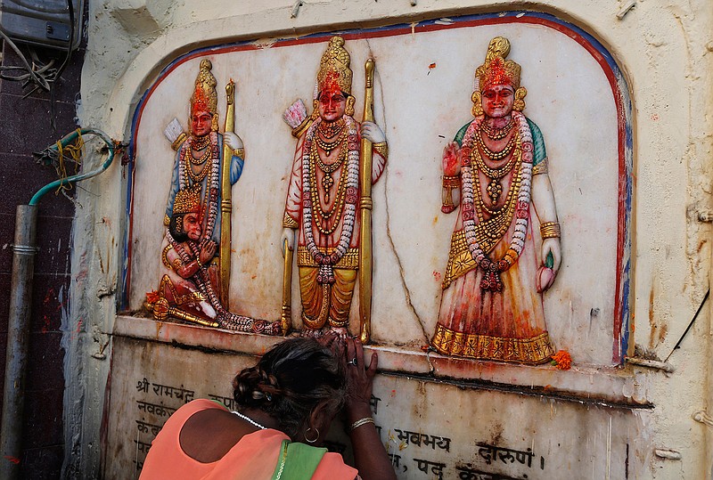 A Hindu pilgrim touches in obeisance an image of Hindu deities Rama, Sita and Lakshman in Ayodhya, India , Saturday, Nov. 9, 2019. India's security forces were on high alert ahead of the Supreme Court's verdict Saturday in a decades-old land title dispute between Muslims and Hindus over plans to build a Hindu temple on a site where Hindu hard-liners demolished a 16th century mosque in 1992, sparking deadly religious riots. (AP Photo/Rajesh Kumar Singh)