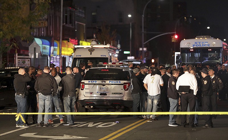 FILE - In this Oct. 25, 2019 file photo, New York police and other emergency personnel investigate the scene of a shooting at a nail salon in the Brownsville neighborhood of the Brooklyn borough of New York. Police say the man who attacked a police officer with a metal chair was shot to death by the officer. A surge in violent police clashes in recent weeks has left a trail of bodies across the city and stoked tensions between officers and critics who say they have been too quick to use deadly force. (AP Photo/Julius Motal, File)