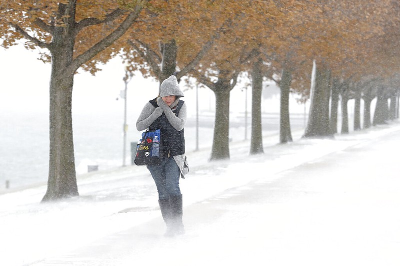 A woman walking the half mile from Chicago's Adler Planetarium to the Chicago Aquarium braces herself in the stiff wind and blowing snow off Lake Michigan Monday, Nov. 11, 2019, in Chicago.