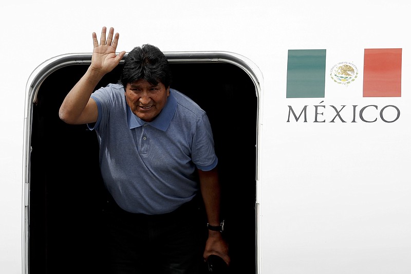 Former Bolivian President Evo Morales waves upon arrival to Mexico City, Tuesday, Nov. 12, 2019. Mexico granted asylum to Morales, who resigned on Nov. 10 under mounting pressure from the military and the public after his re-election victory triggered weeks of fraud allegations and deadly protests. (AP Photo/Eduardo Verdugo)