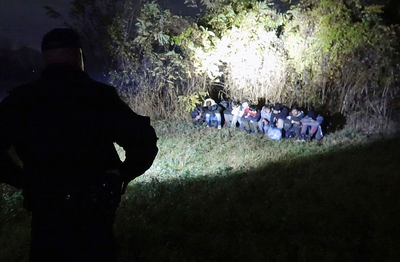 In this photo taken Saturday, Nov. 9, 2019, Bosnian border police officers guard migrants after making the illegal crossing from Serbia by the Drina river, the natural border between Bosnia and Serbia, near eastern Bosnian town of Zvornik, Bosnia. Bosnian border police are warning they cannot contain migratory pressures along the country's eastern border with Serbia, warning the situation could easily escalate and put in danger the overall stability of their politically fragile nation. (AP Photo/Eldar Emric)
