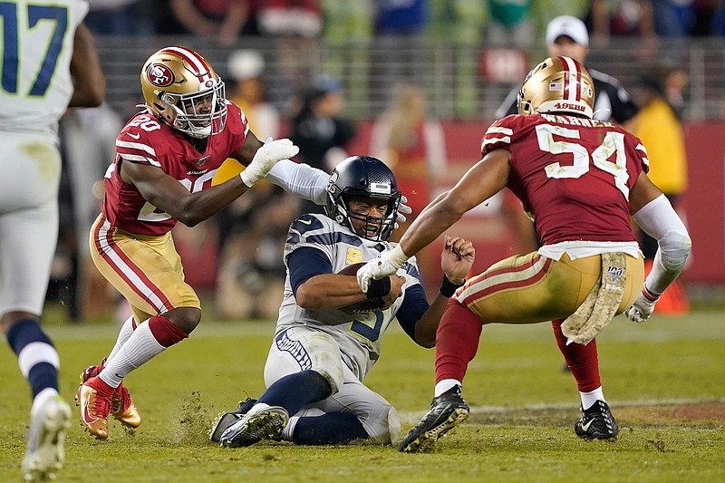 Seattle Seahawks quarterback Russell Wilson (3) slides between San Francisco 49ers free safety Jimmie Ward (20) and middle linebacker Fred Warner (54) during an NFL football game in Santa Clara, Calif., Monday, Nov. 11, 2019. (AP Photo/Tony Avelar)