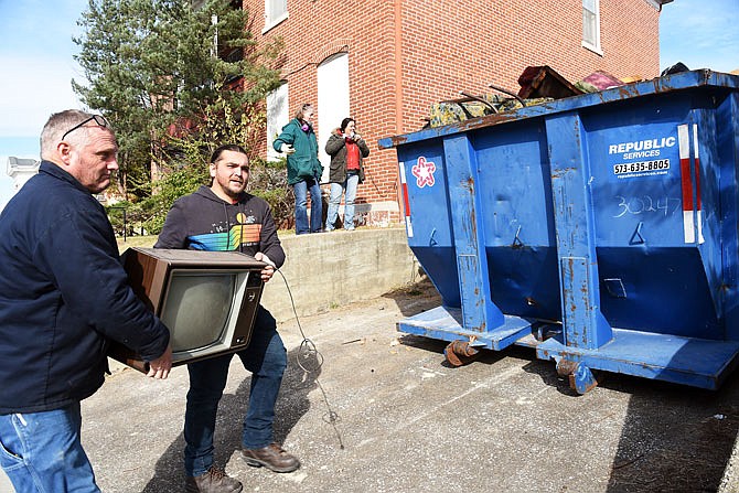 Mitch Verslues, near, and Brandon Johndrow carry out one of several televisions Friday that were left in the house at 501 E. Capitol Ave. Verslues and co-workers from Jefferson City Housing Authority have been cleaning out houses on East Capitol Avenue and Jackson Street that will be open for the public to tour Friday. 