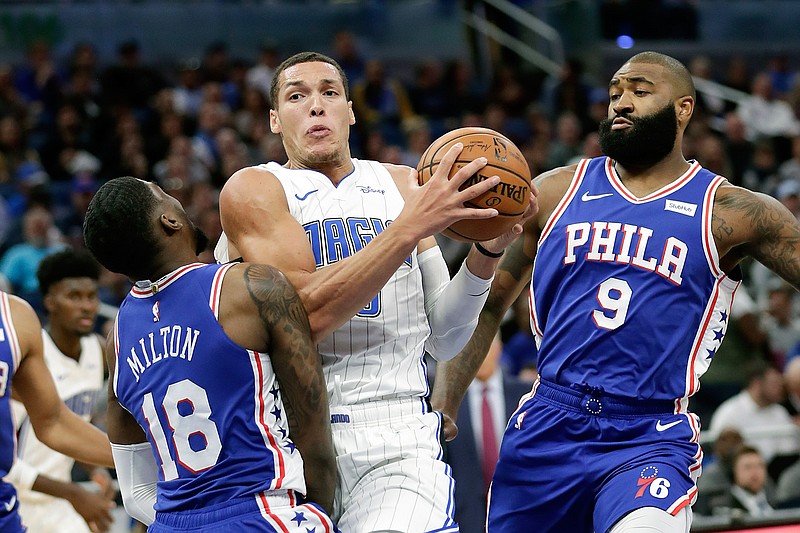 Orlando Magic's Aaron Gordon, center, runs into Philadelphia 76ers' Shake Milton (18), as Kyle O'Quinn (9) helps on defense during the first half of an NBA basketball game Wednesday, Nov. 13, 2019, in Orlando, Fla. Gordon was called for an offensive foul. (AP Photo/John Raoux)