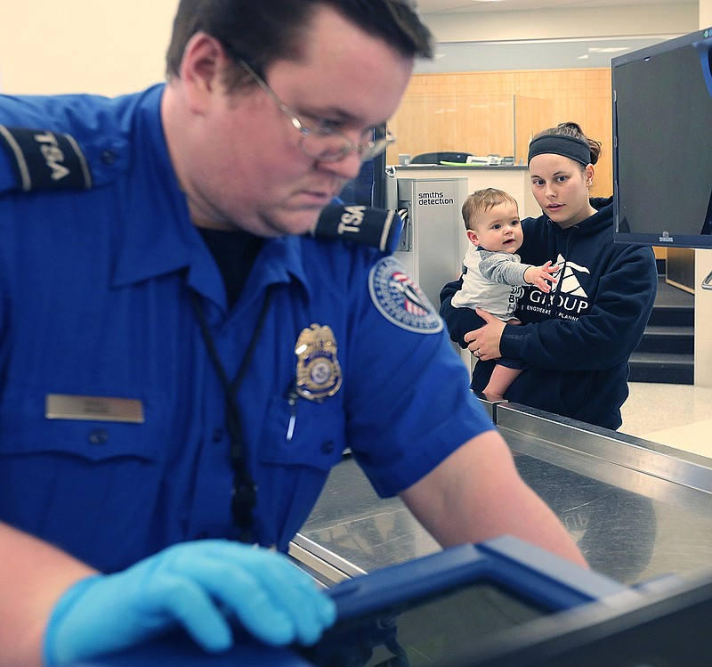 Akron-Canton Airport TSA Agent James Sakel checks a sippy cup belonging to Meghan Mason and her son Daulton, 1, of Norton, Ohio as they head through a security checkpoint in Green, Ohio. It is important to travel with family to see the world through a new perspective. (Phil Masturzo/Akron Beacon Journal/TNS)