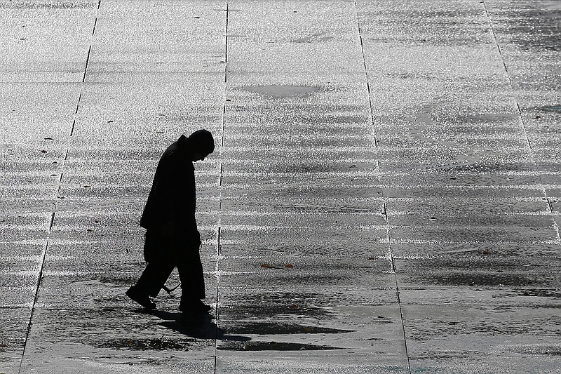 A man walks across the icy Legislative Plaza Tuesday, Nov. 12, 2019, in Nashville, Tenn. Snow and icy conditions are snarling traffic and closing or delaying schools in parts of the Northeast and South. (AP Photo/Mark Humphrey)