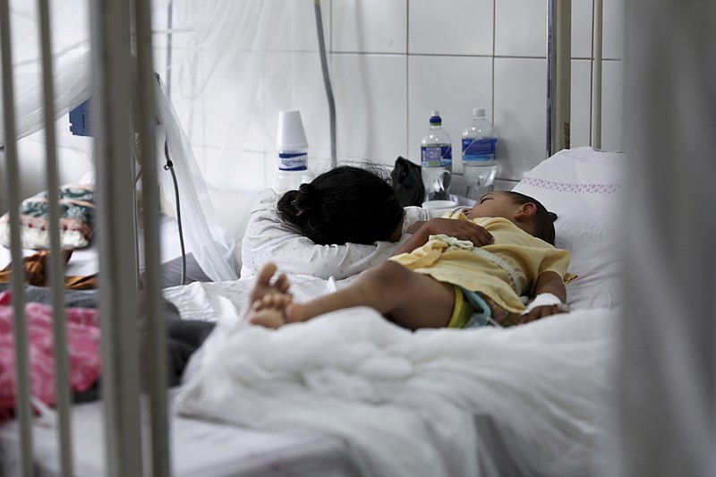 In this Aug. 20, 2019 file photo, a relative embraces a young patient receiving treatment for dengue at the University School Hospital in Tegucigalpa, Honduras. In an international report released on Wednesday, Nov. 13, 2019, doctors  say children are growing up in a warmer world that will hit them with more and different health problems than their parents had. (AP Photo/Eduardo Verdugo)