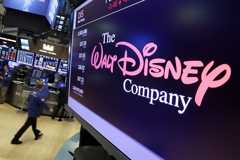 FILE - In this Aug. 8, 2017, file photo, The Walt Disney Co. logo appears on a screen above the floor of the New York Stock Exchange. Disney’s new streaming service, Disney Plus, is adding a disclaimer to "Dumbo," “Peter Pan” and other classics because they depict racist stereotypes, underscoring a challenge media companies face when they resurrect older movies in modern times. (AP Photo/Richard Drew, File)