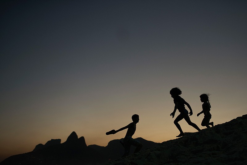 In this Aug. 1, 2016 file photo, children are silhouetted against the setting sun as they run on the sand at Ipanema beach in Rio de Janeiro, Brazil. Homeland Security investigators who uncover child exploitation initiated more than 4,000 cases around the world in 2019. Data obtained by The Associated Press shows the investigations resulted in thousands of arrests and the identification of more than 1,000 victims. On Thursday, Nov. 14, 2019, officials plan to unveil a new center based at Immigration and Customs Enforcement's headquarters in Washington tasked with alerting other countries when U.S. sex offenders are traveling there.  (AP Photo/Felipe Dana, File)