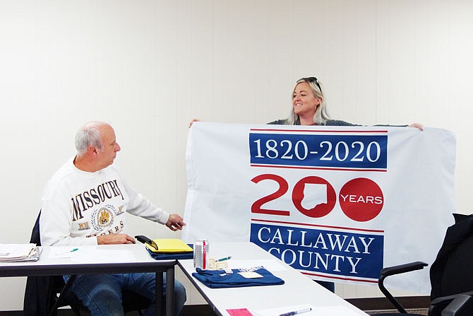 Callaway 200 committee members Doc Kritzer, left, and Lisa Fansler show off a full-sized flag for the occasion. It and other merchandise will be on sale for the first time at tonight's kickoff gala.