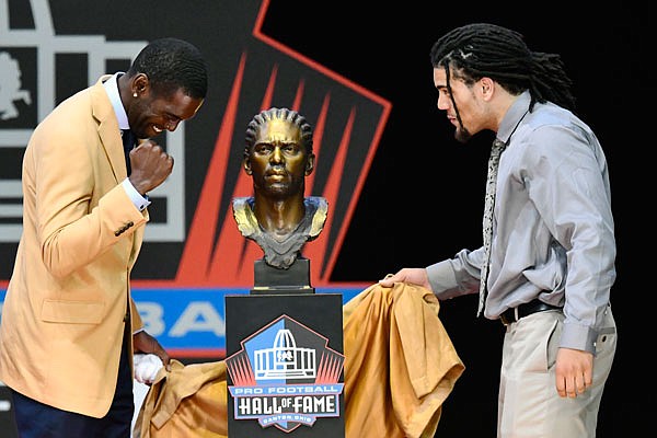 In this Aug. 4, 2018, file photo, former NFL wide receiver Randy Moss (left) unveils his bust with his presenter, son Thaddeus Moss, during induction ceremonies at the Pro Football Hall of Fame in Canton, Ohio.